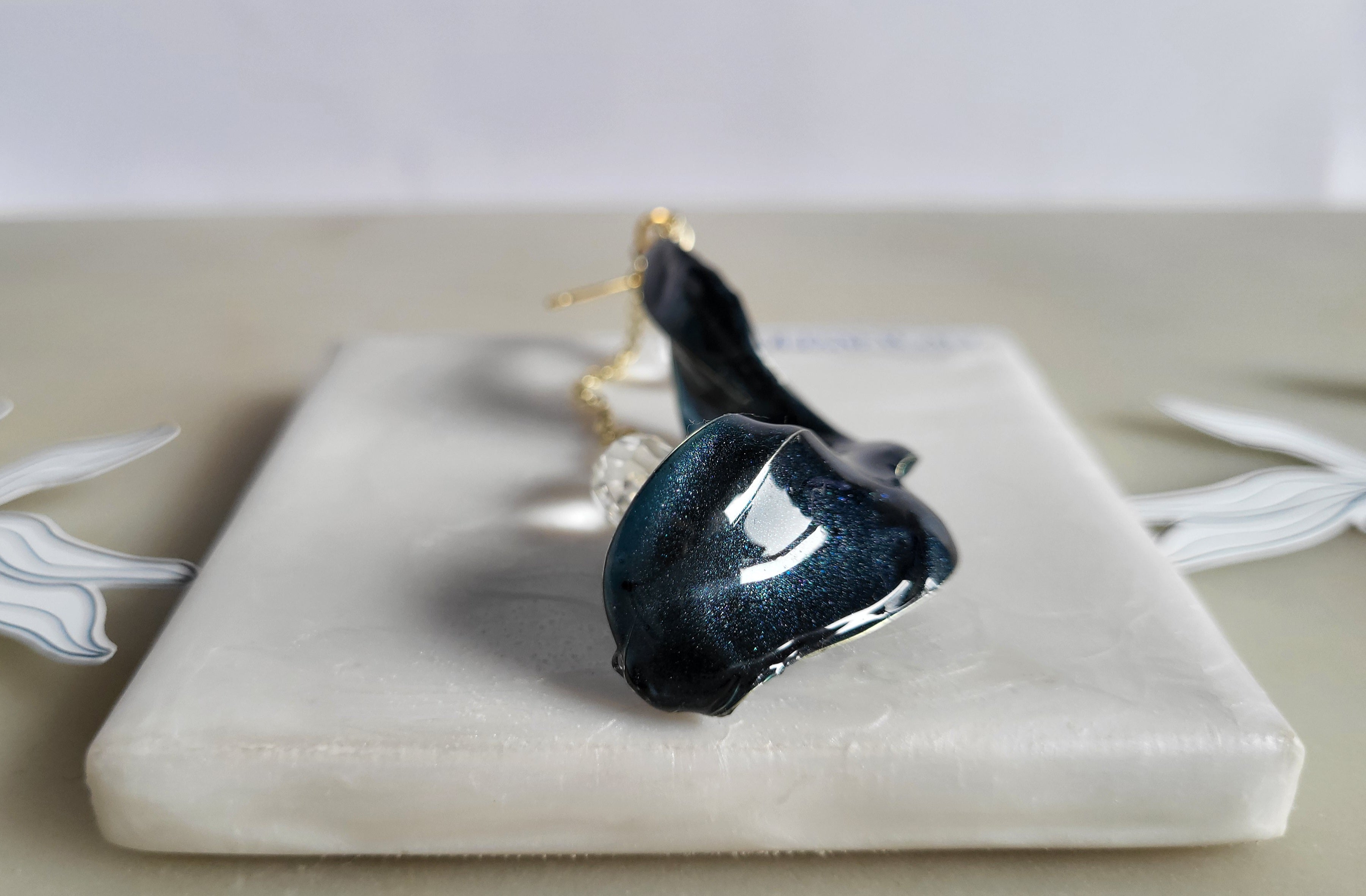 Handcrafted long gold wire earrings with navy blue starry cat eye resin flowers, zirconia starburst crystal studs, waterdrop crystals, and raindrop dangles.