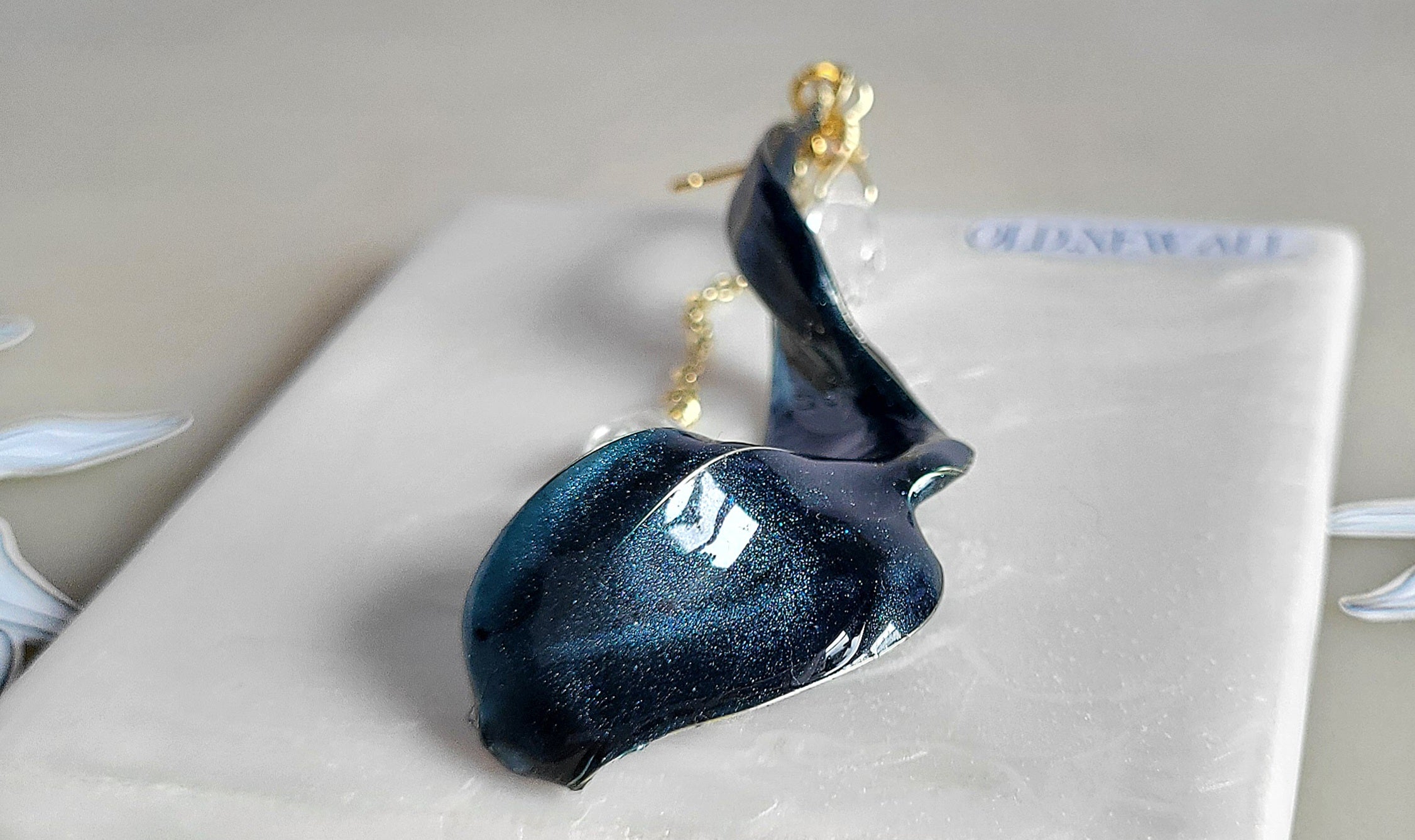 Handcrafted long gold wire earrings with navy blue starry cat eye resin flowers, zirconia starburst crystal studs, waterdrop crystals, and raindrop dangles.