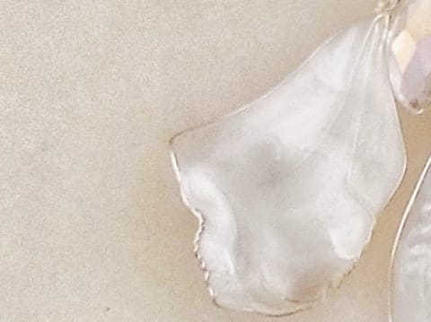 close up Handcrafted white mother-of-pearl resin earrings on silver french hooks with clear crystal suncatcher waterdrops