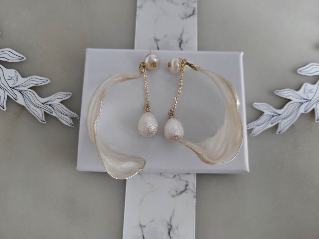 Handcrafted white pearl studs with an embedded gold heart, featuring a delicate chain with a twisted wire white resin petal drop design.