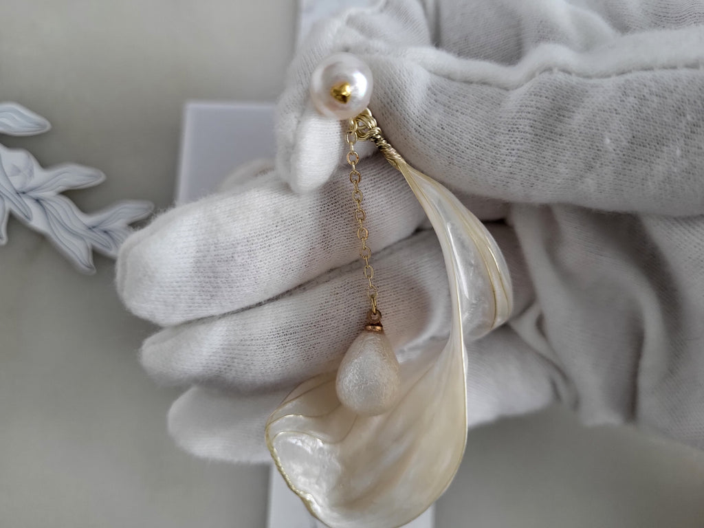 Handcrafted white pearl studs with an embedded gold heart, featuring a delicate chain with a twisted wire white resin petal drop design.