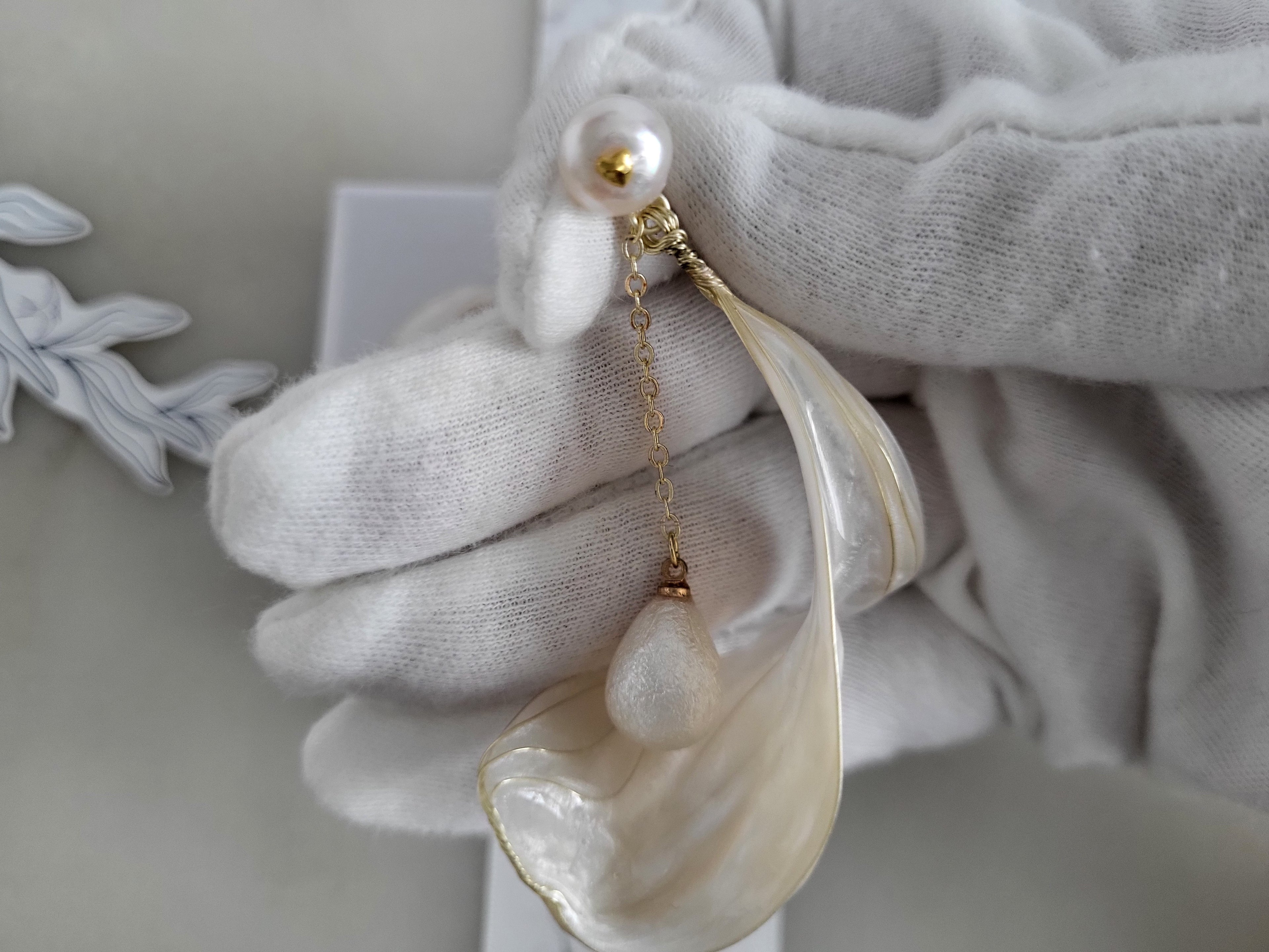 Handcrafted white pearl studs with an embedded gold heart, featuring a delicate chain with a twisted wire white resin petal drop design.