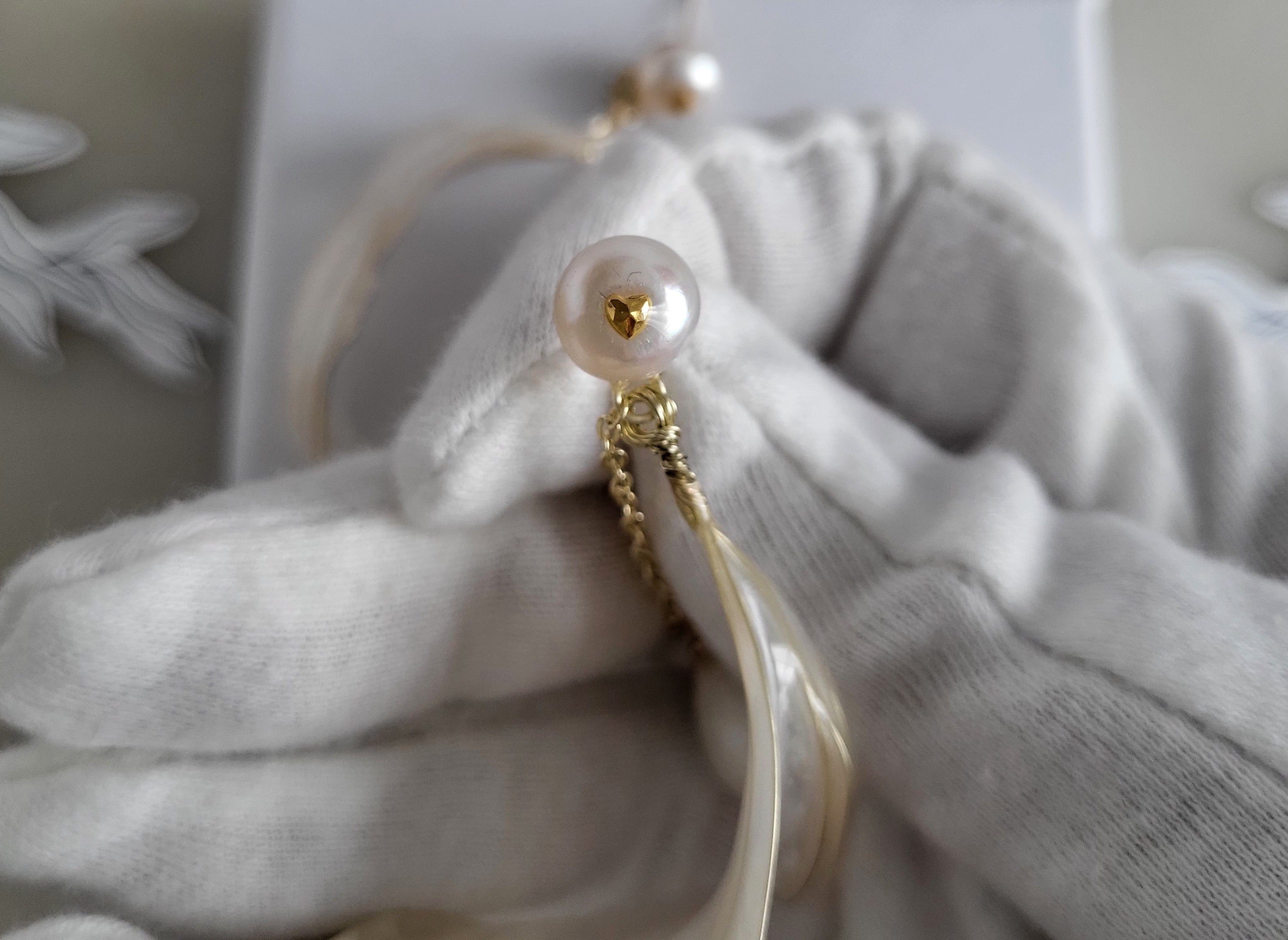Handcrafted white pearl studs with an embedded gold heart, featuring a delicate chain with a twisted wire white resin petal drop design.