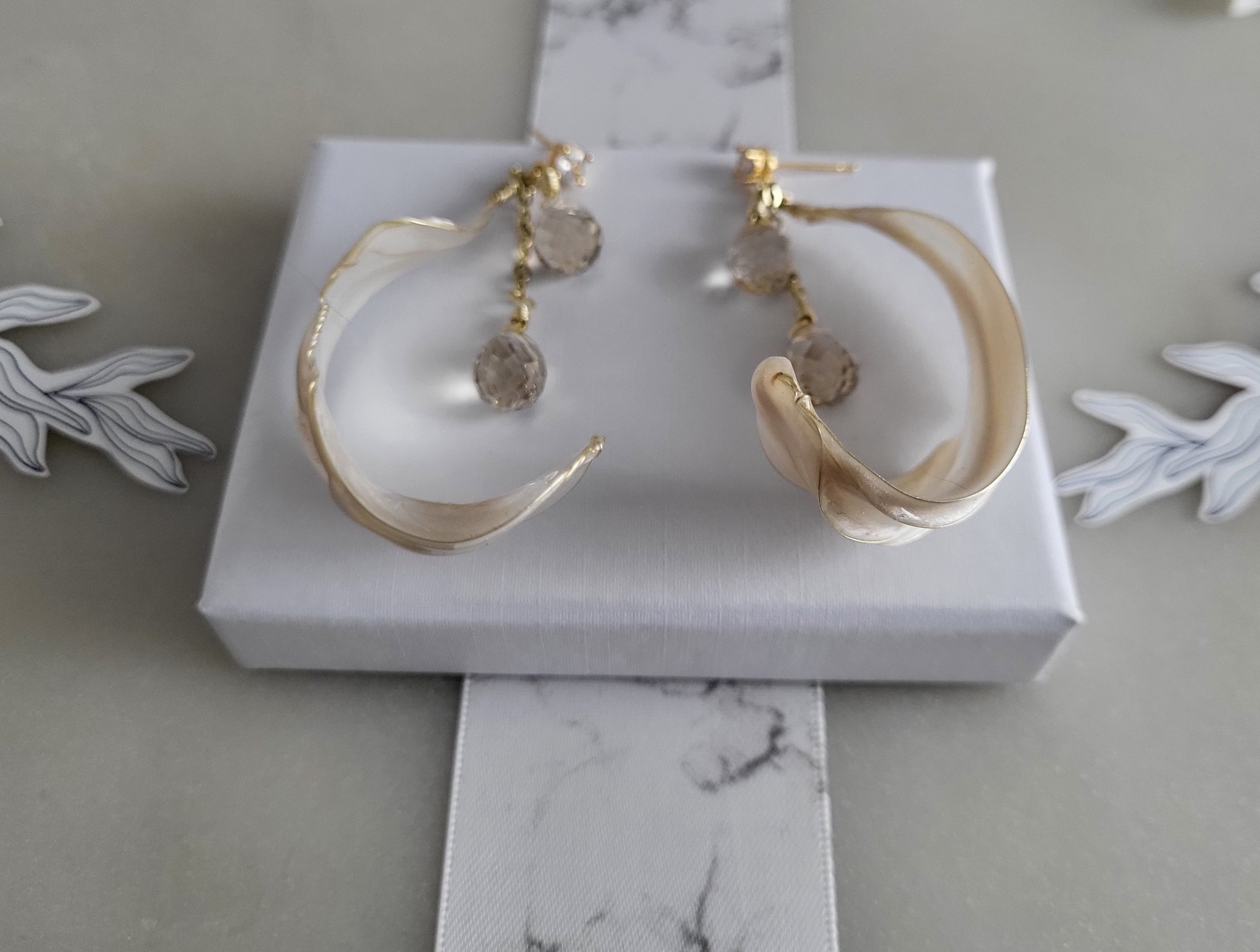 Handcrafted long gold wire earrings with ivory mother of pearl resin flowers on a delicate chain with sparkling champagne crystal drops.