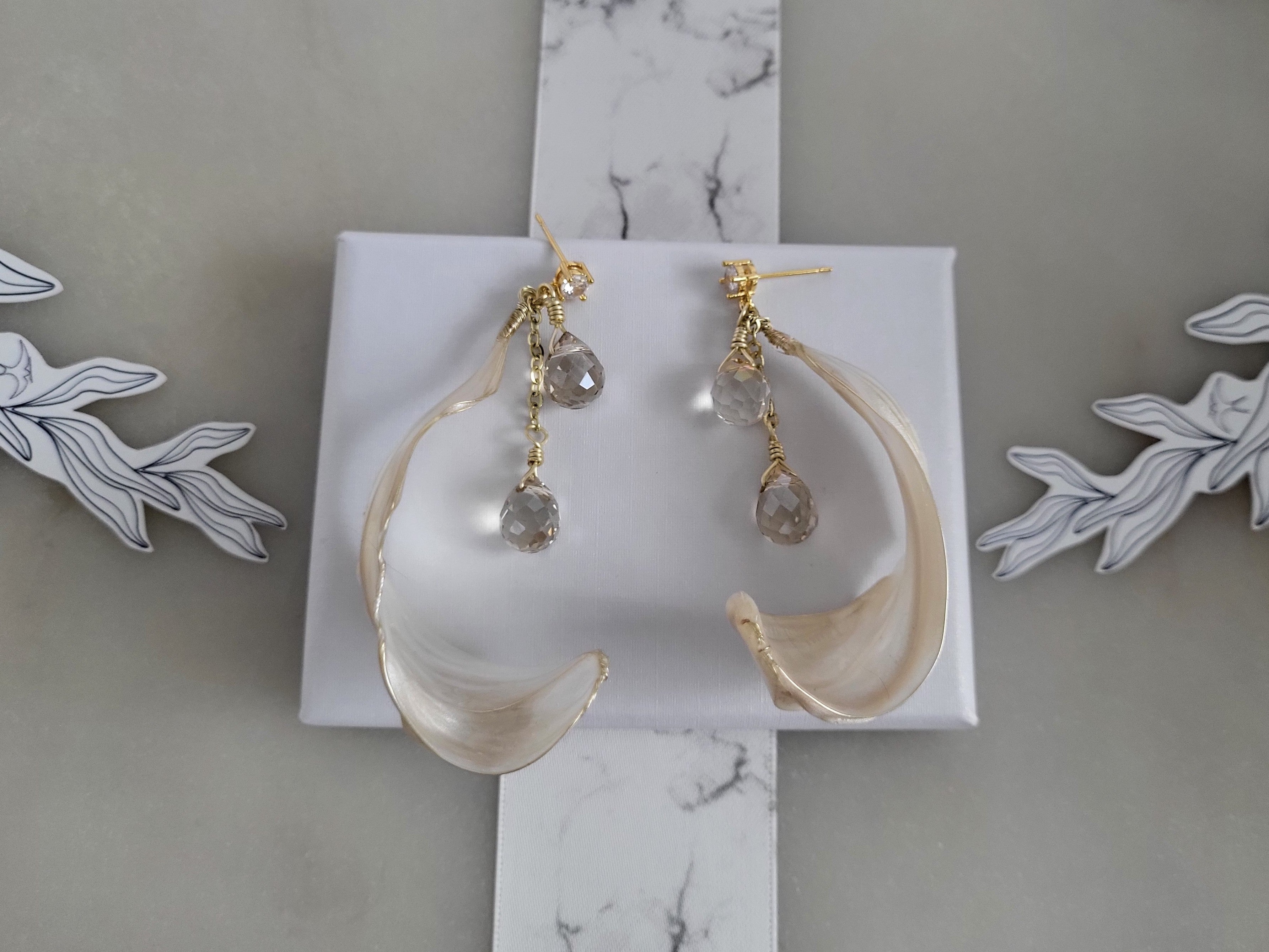 Handcrafted long gold wire earrings with ivory mother of pearl resin flowers on a delicate chain with sparkling champagne crystal drops.