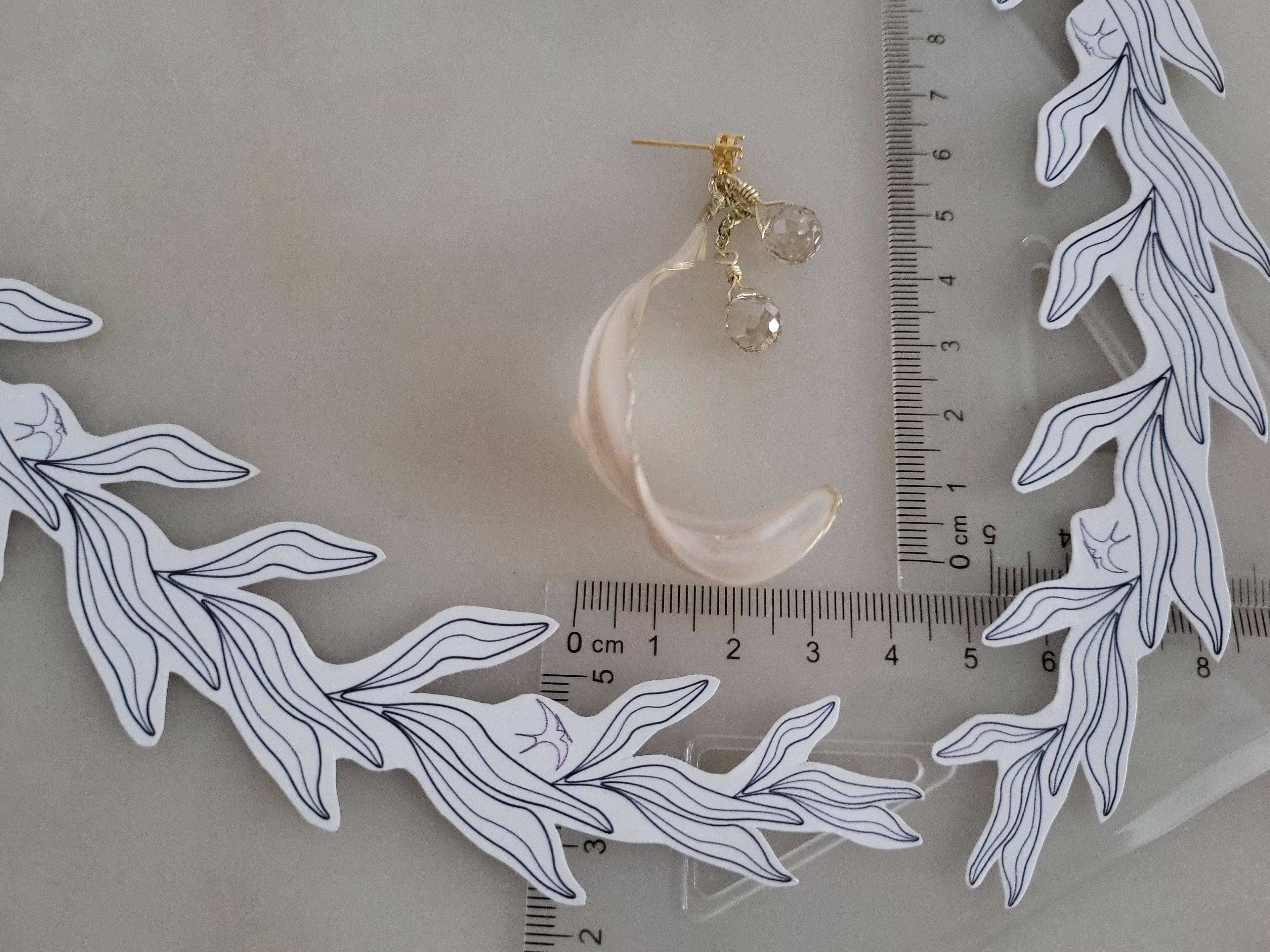 Handcrafted long gold wire earrings with ivory mother of pearl resin flowers on a delicate chain with sparkling champagne crystal drops with a ruler