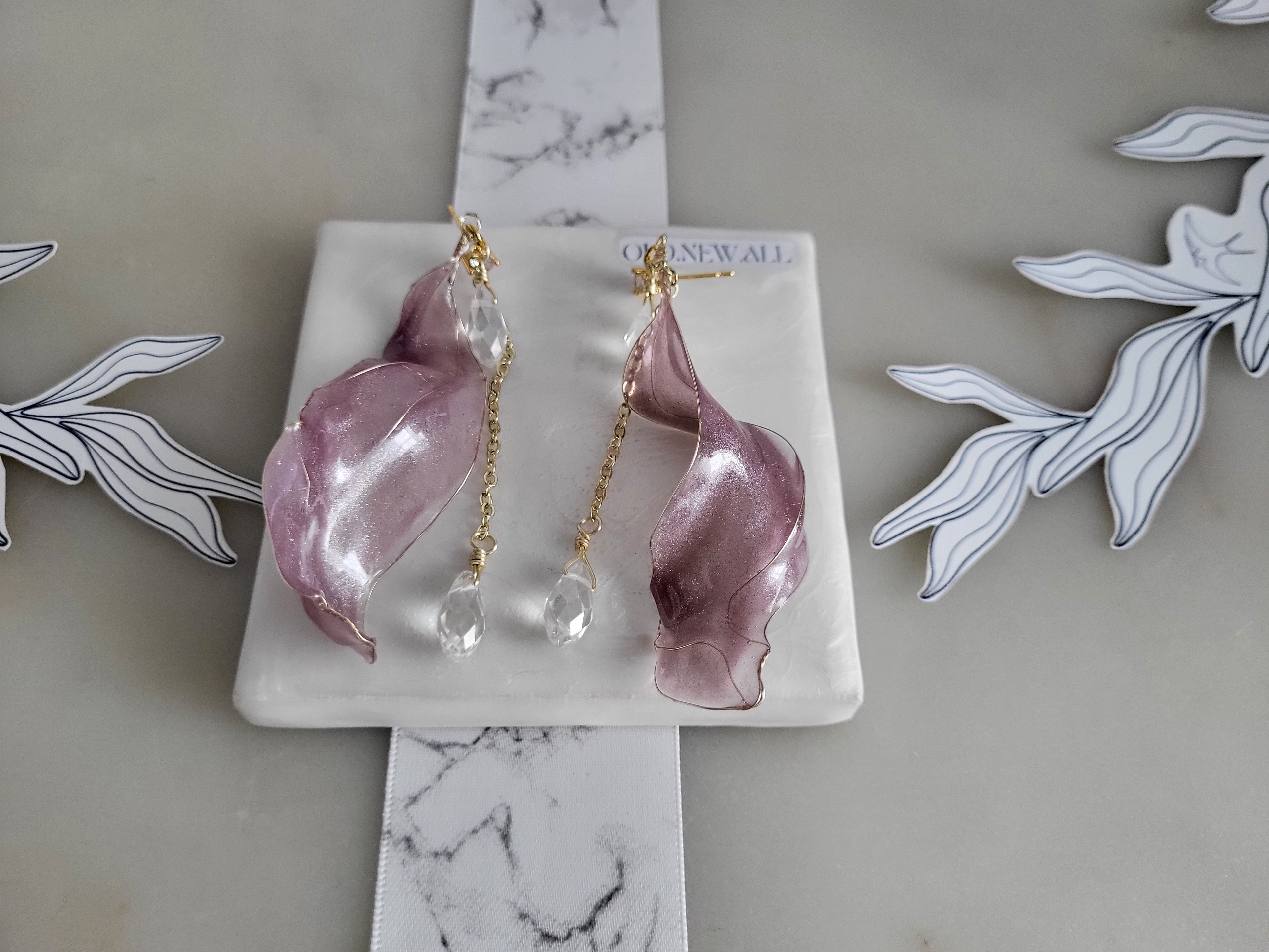 Handcrafted long golden wire earrings featuring pink cat eye resin flowers on a delicate chain with zirconia studs, waterdrop crystals, and raindrop dangles.