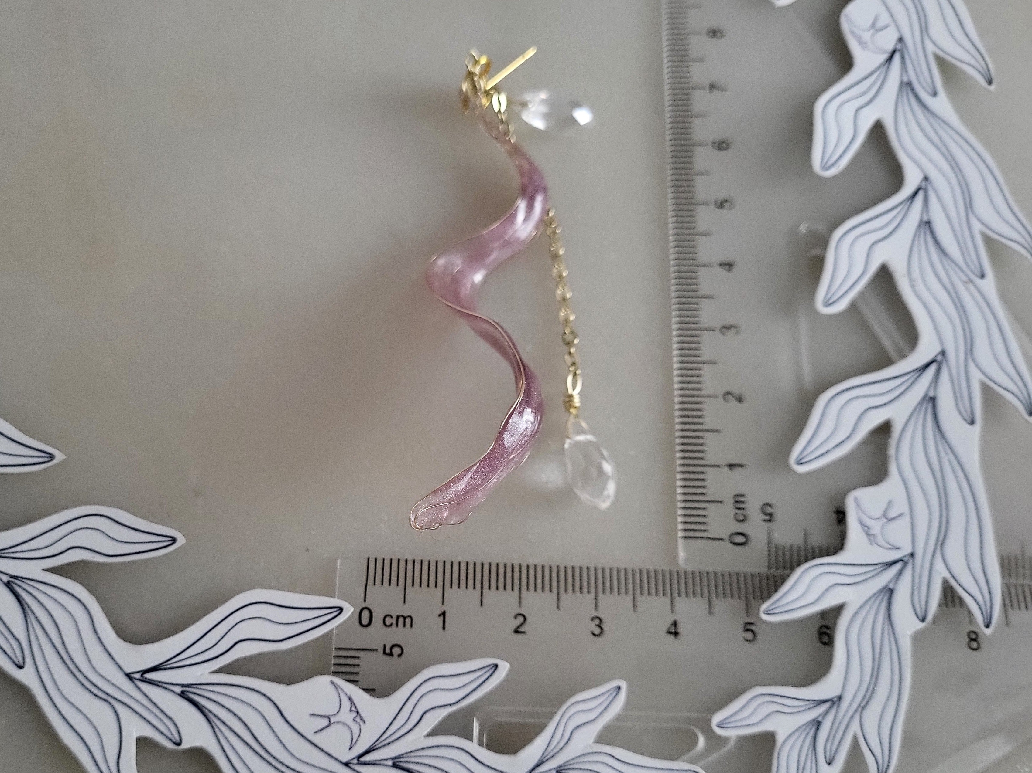 Handcrafted long golden wire earrings featuring pink cat eye resin flowers on a delicate chain with zirconia studs, waterdrop crystals, and raindrop dangles.