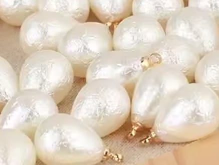 Close-up of white pearls with gold clasps on a wooden surface