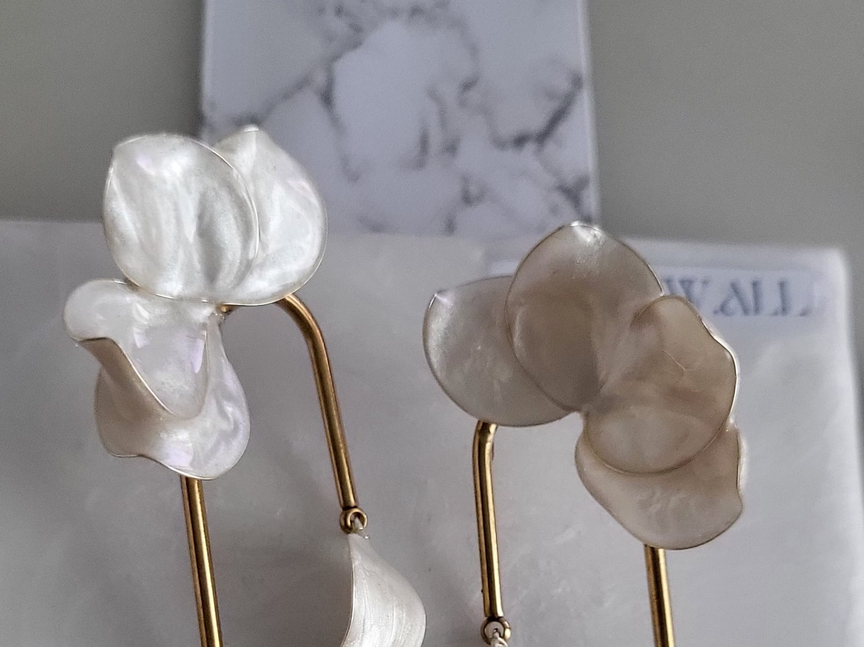 Large handcrafted flower earrings with opaque pearlescent petals and bridal aesthetic charms, displayed on a natural wood surface.