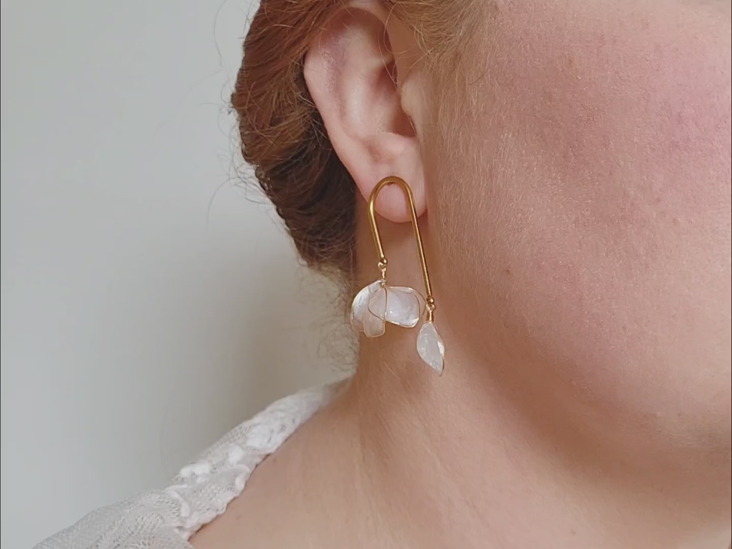 Handcrafted golden arch mismatched tulip earrings featuring a translucent white resin flower charm and a dangling motherofpearl petal drop.